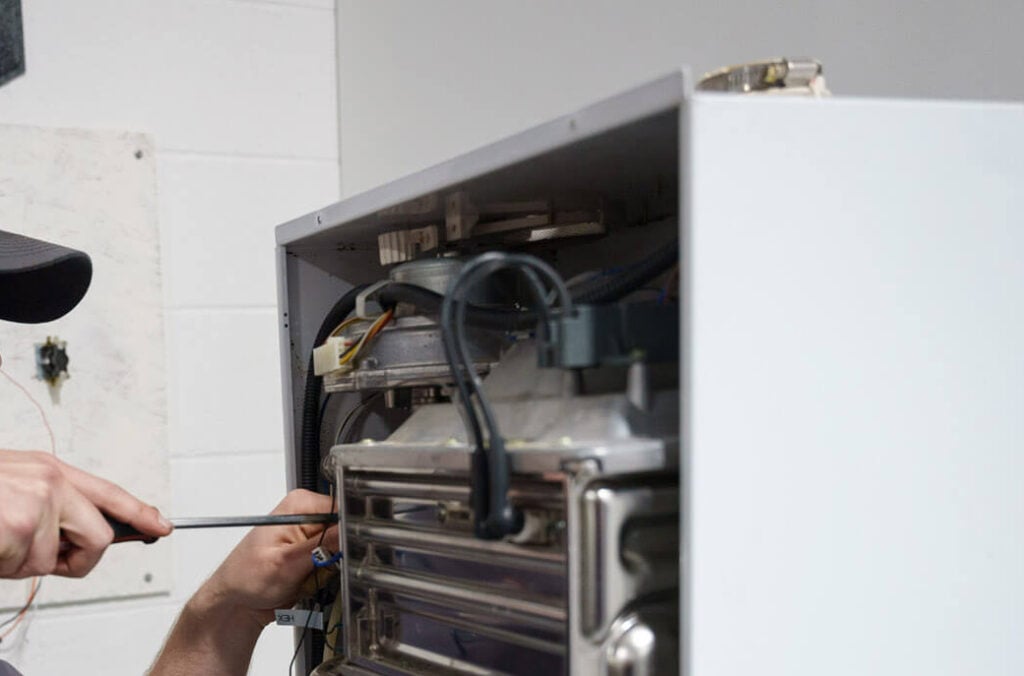 A Russell's and American Mechanical technician servicing a heating unit in Chesapeake, VA.